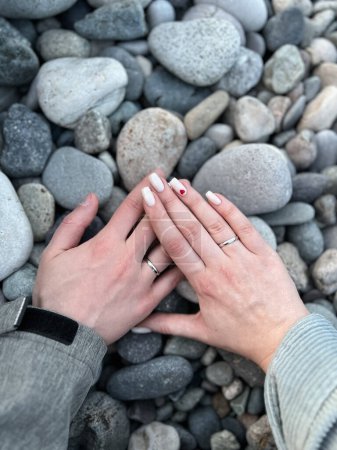 Husband and wife's hands with wedding rings on the background of stones. High quality photo