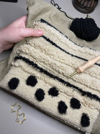 Poinçon broderie en laine noire et beige. Photo de haute qualité. Main avec broderie en laine et aiguille à poinçonner .