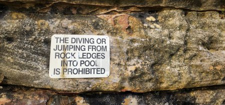 Foto de Un letrero sobre El buceo o saltar de las repisas de roca en la piscina está prohibido, incrustado en la piedra - Imagen libre de derechos