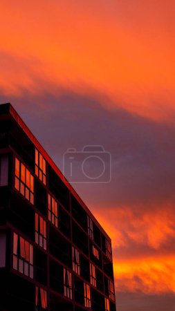 Spiegelndes Gebäude, komplett rot mit der Reflexion des Sonnenuntergangs, als ob es heiß und in Flammen stünde, im Dee Why-Viertel in Sydney, Australien.