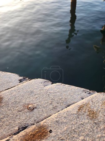Abstract image of sea water next to a pier, a wooden deck painted white, in a sunset light