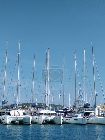 Sailing yachts are lined up in the marina on a sunny day