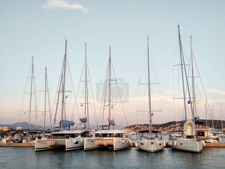 Sailing yachts stand in a row in the marina at sunset