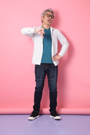 Asian senior man in casual clothing with gesture of thumbs down isolated on pink background. St Valentine's Day