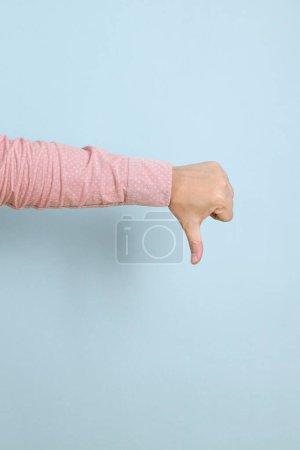 Close up hands of  asian male hand gesture of thumbs down isolated on pink background.