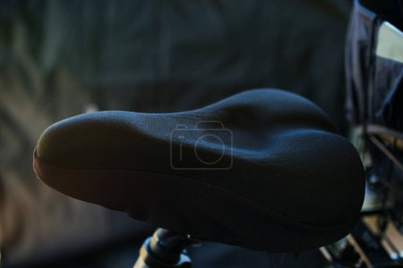 Schwarzer gepolsterter Fahrradsitz vor schwarzem Hintergrund.