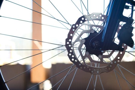 Nahaufnahme des Vorderrades eines E-Bikes mit einer Edelstahl-Bremsscheibe, Bremssattel und einem Teil der dunkelblauen Hochglanzgabel.