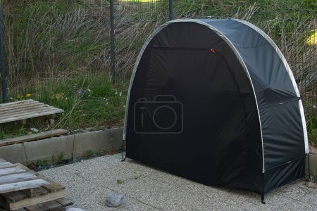 Closed black bicycle tent with a zipper closure, set outdoors.