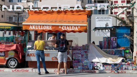 Foto de Durres, Albania - 13 de abril de 2024 - Foto de dos personas comprando helado en una pequeña tienda junto a la carretera a lo largo del paseo marítimo. - Imagen libre de derechos