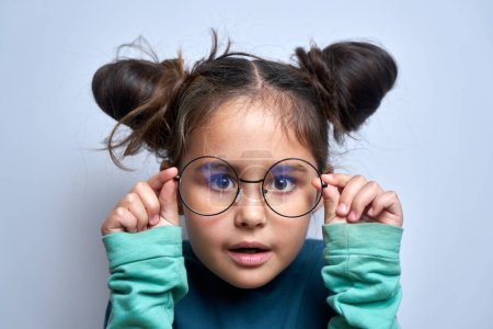 Photo for Caucasian little girl wearing glasses squinting while looking at camera isolated on white background. Vision problems concept - Royalty Free Image