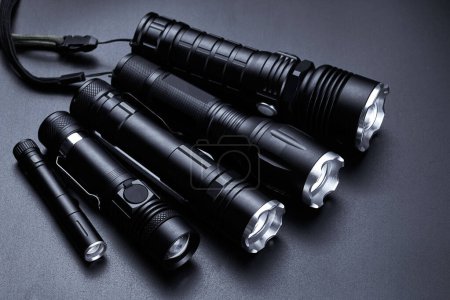 Téléchargez les photos : Ensemble de lampes de poche tactiques noires isolées sur fond noir - en image libre de droit