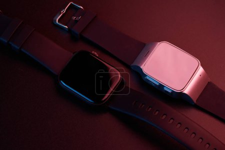 Foto de Reloj inteligente electrónico inalámbrico con pantalla táctil de primer plano aislado sobre fondo rojo. Pulsera Bluetooth, rastreador de fitness de banda negra - Imagen libre de derechos