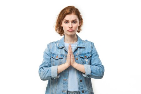 Téléchargez les photos : Portrait de jeune rousse femme plié les mains dans un geste de prière isolé sur fond blanc. Paisible, reconnaissant, confiant, fait un concept de souhait - en image libre de droit