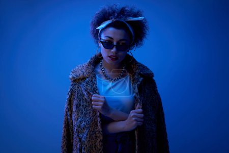 Photo for Close-up face portrait of cool kazakh model girl with curls and chain posing in leopard fur coat in neon light isolated on studio background - Royalty Free Image