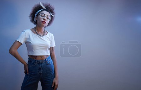 Photo for Portrait of cool Kazakh girl with curls and tattoo posing in neon light isolated on studio background - Royalty Free Image