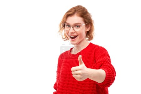 Téléchargez les photos : Jeune rousse femme montre la main avec les pouces vers le haut et sourit à la caméra isolée sur fond blanc - en image libre de droit