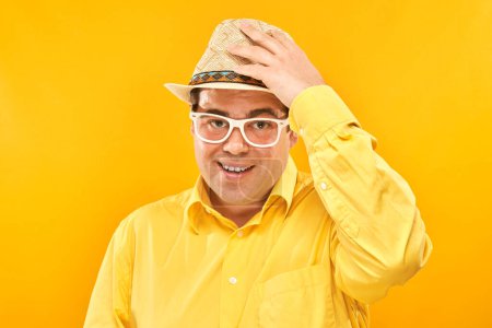 Photo for Portrait of positive fat man in hat kindly smiling isolated on yellow studio background, travel vacation concept - Royalty Free Image