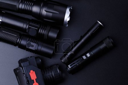 Téléchargez les photos : Ensemble de lampes de poche tactiques noires isolées sur fond noir - en image libre de droit