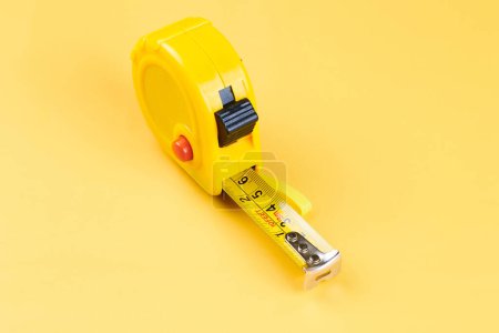 Téléchargez les photos : Ruban à mesurer jaune menuisier avec centimètres isolés sur fond jaune. Outil de construction. - en image libre de droit