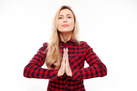 Téléchargez les photos : Portrait de jeune femme blonde plié les mains dans un geste de prière isolé sur fond blanc. Paisible, reconnaissant, confiant, fait un concept de souhait - en image libre de droit