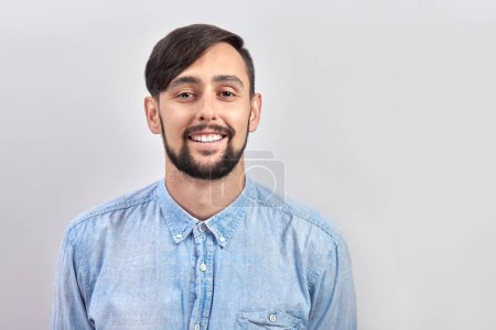 Photo pour Portrait de jeune caucasien brunette barbu mâle positif sourire isolé sur fond de studio blanc - image libre de droit