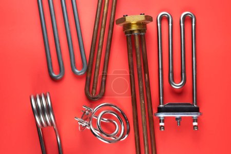 Foto de Set de diferentes tipos Elementos calefactores tubulares de acero para lavadoras, agua hirviendo, calefacción, aislados sobre fondo rojo - Imagen libre de derechos