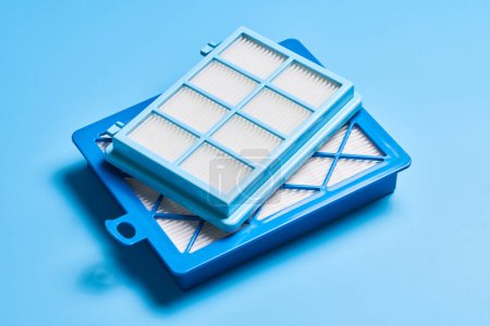 Foto de Nuevos filtros de aire de polvo limpio para aspiradora aislada sobre fondo azul - Imagen libre de derechos