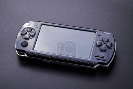 Téléchargez les photos : Console de jeu vidéo portable hybride portable avec commutateur contrôleurs amovibles des deux côtés isolé sur fond noir, gadget sans fil - en image libre de droit