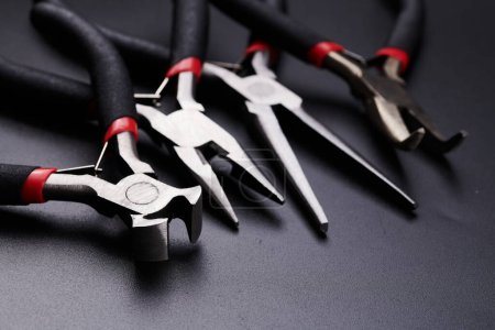 Photo for Set of different types of pliers and side cutters isolated on black background. Hand tools for repair, construction and maintenance - Royalty Free Image
