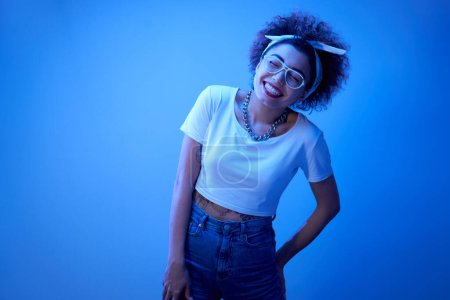 Photo for Portrait of cool Kazakh girl with curls and tattoo posing in neon light isolated on studio background - Royalty Free Image