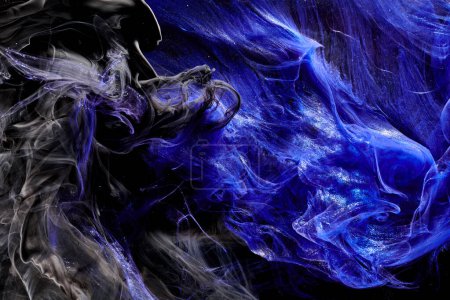 Téléchargez les photos : Fond bleu foncé abstrait océan. Éclaboussures, gouttes et vagues de peinture brillante sous l'eau, nuages de fumée en mouvement - en image libre de droit