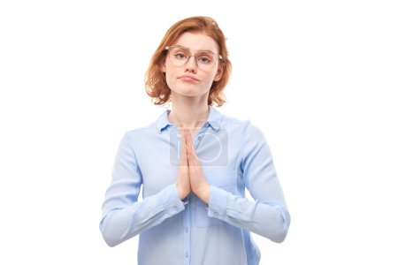 Téléchargez les photos : Portrait de jeune rousse femme plié les mains dans un geste de prière isolé sur fond blanc. Paisible, reconnaissant, confiant, fait un concept de souhait - en image libre de droit