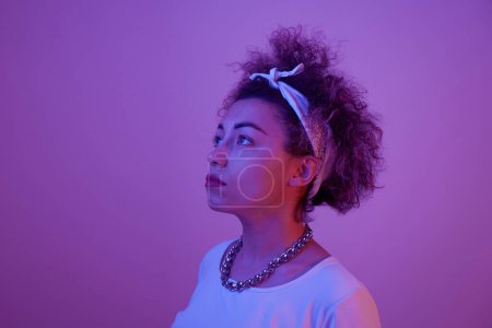 Photo for Close-up face portrait of cool kazakh model girl with curls and chain in neon light isolated on studio background - Royalty Free Image