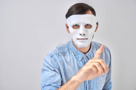 Photo for Mystery man in white mask on his face isolated on studio background - Royalty Free Image