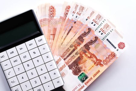 Téléchargez les photos : Roubles russes cinq millième billets de banque, calculatrice et pile d'argent sur fond blanc - en image libre de droit