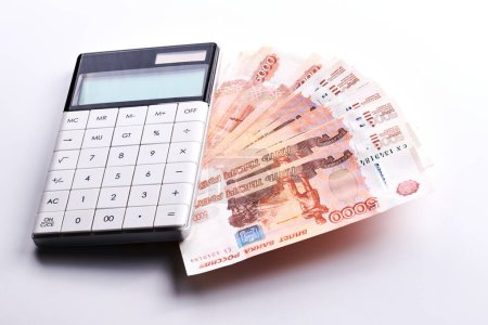 Foto de Rublos rusos cinco mil billetes, calculadora y pila de dinero sobre fondo blanco - Imagen libre de derechos