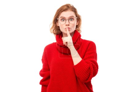 Photo for Portrait of young redhead woman covering mouth with finger isolated on white background. Asks for silence, keep secret, shh gesture - Royalty Free Image