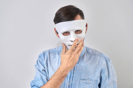 Foto de Hombre misterioso con máscara blanca en su rostro aislado en el fondo del estudio - Imagen libre de derechos