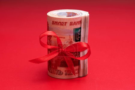Foto de Rublos rusos cinco mil billetes, paquete de dinero con cinta roja sobre fondo rojo, concepto de regalo - Imagen libre de derechos