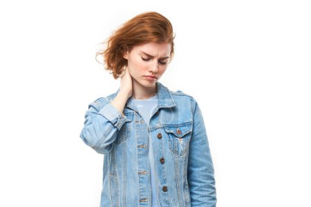 Téléchargez les photos : Portrait rousse jeune femme au visage souffrant ressent de la douleur dans son cou isolé sur fond de studio blanc - en image libre de droit