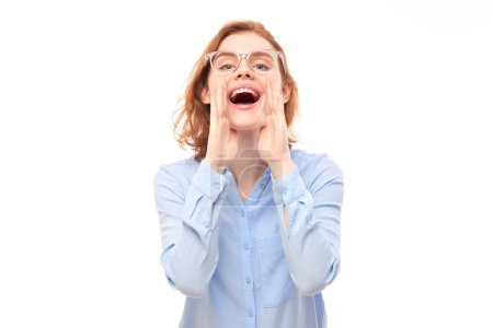 Portrait of redhead young woman screaming into her palms on white studio background. Important information, news concept