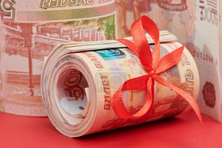 Téléchargez les photos : Roubles russes cinq mille billets de banque, paquet d'argent avec ruban rouge sur fond rouge, concept de cadeau - en image libre de droit