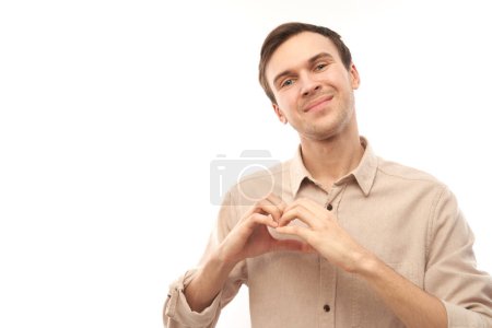 Téléchargez les photos : Portrait heureux jeune homme caucasien fait geste de coeur, demande à être ma valentine. Ami garder les mains sur la poitrine, se sentir reconnaissant isolé sur fond de studio blanc - en image libre de droit