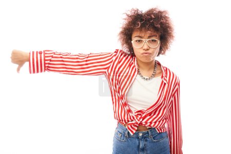 Photo for Portrait of displeased young brunette curly woman showing thumbs down isolated on white studio background. Does not approve of something, puts a dislike - Royalty Free Image