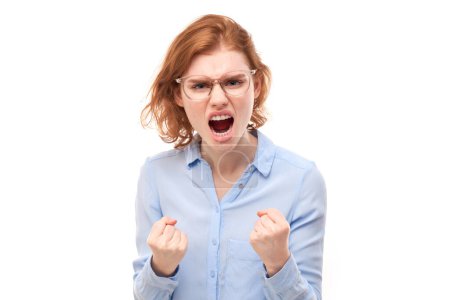 Foto de Retrato enojado pelirroja joven gritando aislado en el fondo del estudio blanco, mostrando emoción negativa - Imagen libre de derechos
