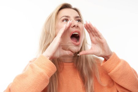 Foto de Retrato de una joven rubia gritando en sus palmas sobre fondo blanco del estudio. Información importante, noticias concep - Imagen libre de derechos
