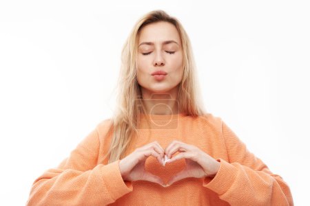 Photo for Portrait of happy young blond woman makes heart gesture, asks to be my valentine. Girlfriend keep hands on chest, feel thankful isolated on white studio background - Royalty Free Image