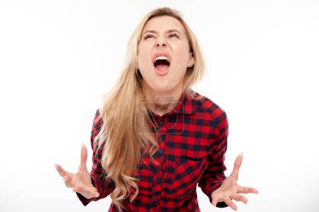 Foto de Retrato enojado rubia joven gritando aislado en el fondo del estudio blanco, mostrando emociones negativas - Imagen libre de derechos