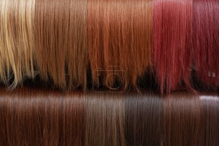 Foto de Escaparate de pelucas de aspecto natural en diferentes colores en el salón de belleza, matices de variación de cabello en el estante en la tienda de pelucas - Imagen libre de derechos