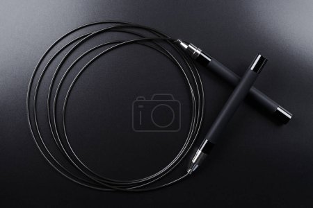 Photo for Black fitness skipping rope close-up on black background. Crossfit sports equipment - Royalty Free Image